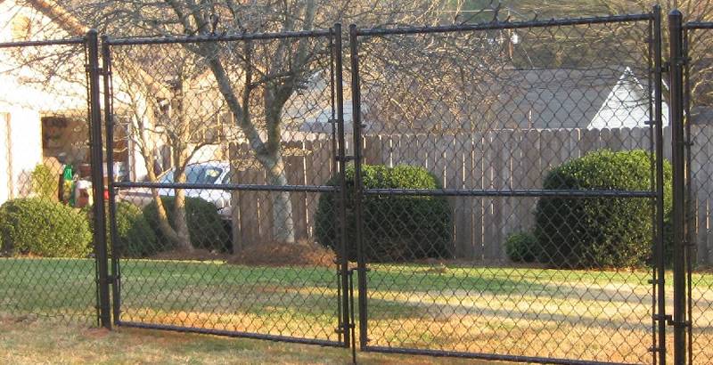 Black vinyl-coated chain link fencing gate with horizontal bracing.